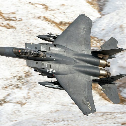 Fighter jet in flight over snowy terrain